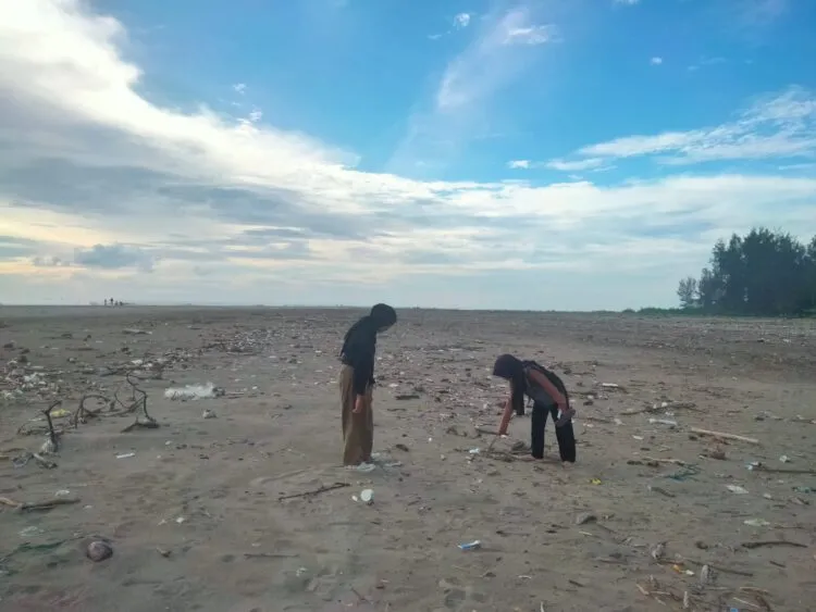Pengunjung sedang memunguti sampah di Pantai Cinta, Pasir Jambak, Senin (22/1/2024) (Genta Andalas/Zulkifli Ramadhani)