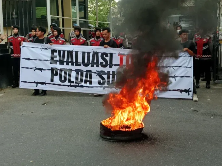 Massa aksi evaluasi 100 hari kerja Kepala Kepolisian Daerah Sumatera Barat melakukan demonstrasi membakar ban di depan kantor Polda Sumbar, pada Senin (21/4/2025) ( Oktavia Ramadhani)